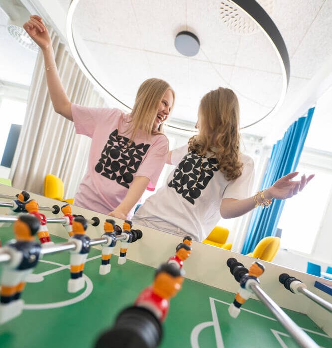 Kaksi nuorta pelaamassa pöytäjalkapalloa